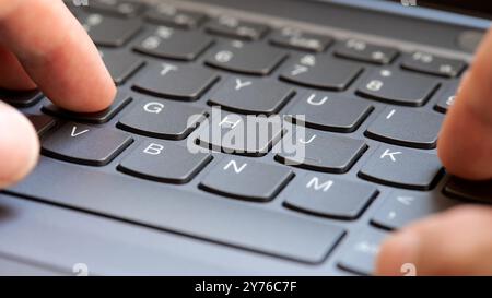Man typing fast on a new gray modern laptop keyboard, closeup, real time, one person. Creative content writing, quickly typing something on a keyboard Stock Photo