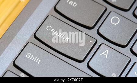 Man pressing the Capslock key on a modern laptop computer keyboard, capital letters simple concept, finger pressing the CapsLk key up close detail. On Stock Photo