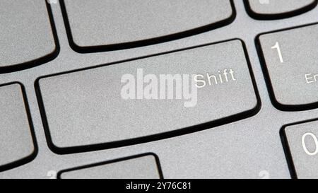 Man pressing the shift key on a modern laptop computer keyboard closeup top view, one person. Shift button key, shifting changing simple abstract conc Stock Photo