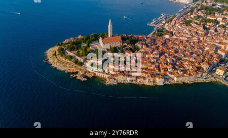 This vibrant coastal town features a charming mix of historic architecture and shimmering blue waters. Discover Rovinj's stunning skyline with its iconic tower and bustling marina during sunset. Stock Photo