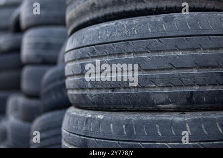 A pile of old tires stacked on top of each other. The tires are black and appear to be worn out. Concept of neglect and abandonment, as the tires are Stock Photo