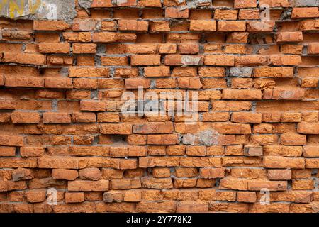 A red brick wall with a few missing bricks. The wall is old and has a rough texture. Stock Photo