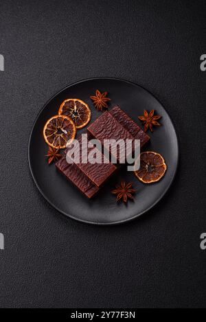 Rectangular chocolate candies with mousse and waffles on a dark concrete background Stock Photo