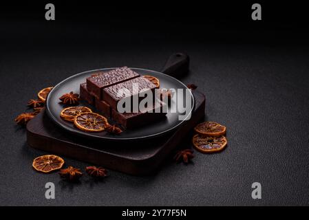 Rectangular chocolate candies with mousse and waffles on a dark concrete background Stock Photo