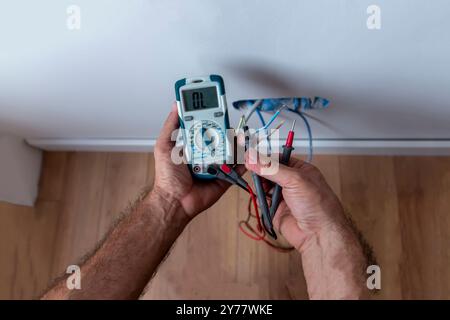 Measuring the voltage in the socket with a professional digital multimeter.  Process of installing sockets. Close-up, selective focus. Stock Photo