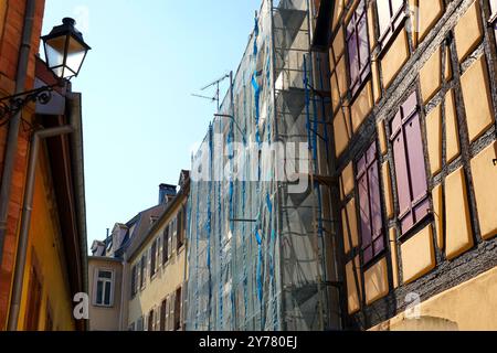 Ancient building in the French city of Colmar is currently undergoing construction, encased in scaffolding and enveloped by a blue safety net. Stock Photo