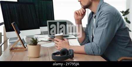 Programmer with coffee working at desk in office, closeup. Banner design Stock Photo