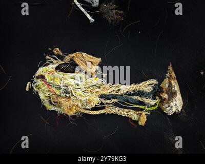 There is a pile of tightly wound rope and colorful yarn on a black ...