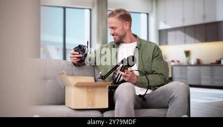 Smiling Young Man Sitting On Sofa Unpacking Received Parcel Stock Photo