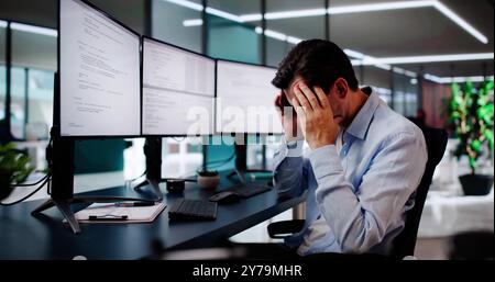 Unhappy Sad Developer Programmer Man In Stress Coding Software On Computer Stock Photo