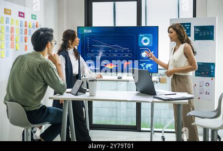 asian worman leader presenting a financial data and strategies in a modern office with charts and graphs displayed on a large screen Stock Photo