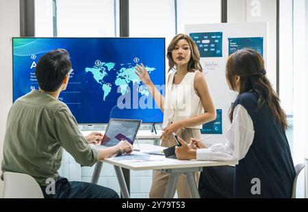 asian leader presenting a financial data and strategies in a modern office with charts and graphs displayed on a large screen Stock Photo