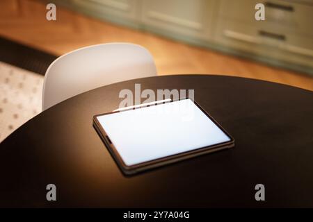 Home kitchen table. Graphic tablet computer. Blank screen reader mockup. Real estate interior. Stock Photo
