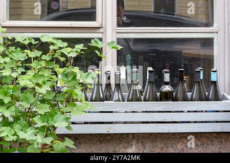 Empty wine bottles in a wooden box near the window of a street cafe. Stock Photo