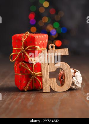 Fifteenth December Wooden number fifteen with red Christmas gift boxes on blurred Christmas lights Stock Photo