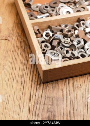Old rusty bolts and nuts in a wooden box on a workbench Stock Photo