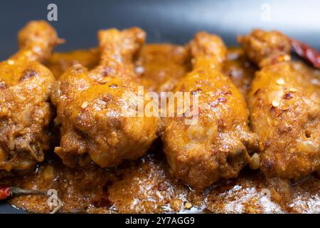 Chicken curry or masala, indian style chicken curry using fried coconut in traditional way and arranged in a black ceramic vessel. Copyspace backgroun Stock Photo