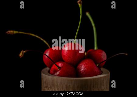 Collection of fresh cherries on a dark background, dynamic shot with action, splash, water drops and bokeh. Fresh fruit floating or levitating shotwit Stock Photo