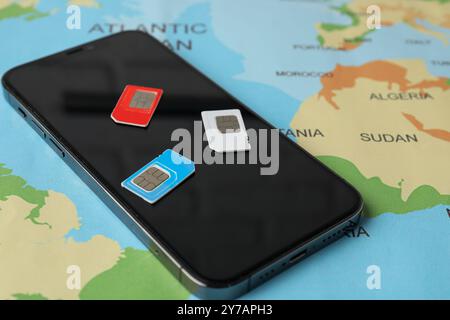 SIM cards and smartphone on world map, closeup Stock Photo