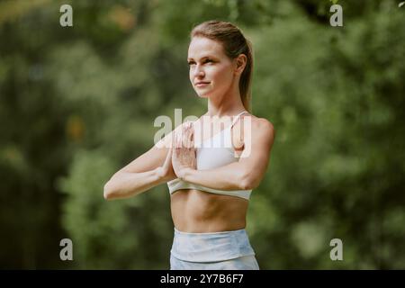 Confident young woman standing in tree pose while practicing yoga in open air Stock Photo