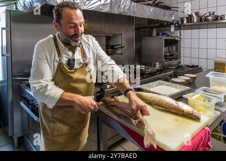 Chef René Bobzin prepares boneless fish with various potato dishes in the kitchen of Bobzin's Bauernstube and presents them personally at the diners' table. Dewichower Straße, Usedom-Süd, Mecklenburg-Vorpommern, Germany Stock Photo