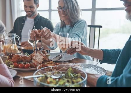 Happy multi-generation family holding hands and praying before having dinner Stock Photo