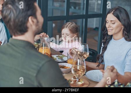 Happy multi-generation family holding hands and praying before having dinner Stock Photo
