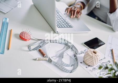 Top view close-up of African woman using laptop while sitting at the desk in fashion design studio Stock Photo