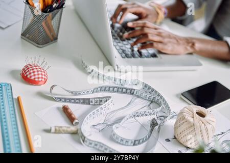 Top view close-up of African woman using laptop while sitting at the desk in fashion design studio Stock Photo