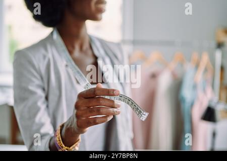 Close-up of young African woman using tape measure while working in design studio Stock Photo