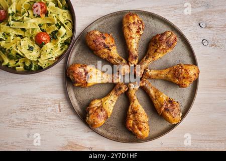 Delicious grilled spiced chicken drumsticks thai recipe, ready to be served with penne rigate with blue cheese sauce and spinach Stock Photo