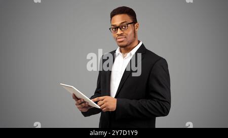 Black guy in suit standing with tablet Stock Photo