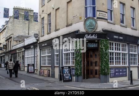 24 April 2024 Pedestrians pass by Belushi's Pub at the junction of Broad Street and Green Street in the City of Bath, Somerset England on a quiet afte Stock Photo