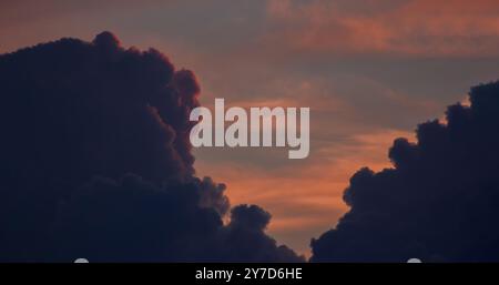 Defocus, a dramatic orange sky between dark thick clouds that are illuminated by a red sunset and hidden behind clouds Stock Photo