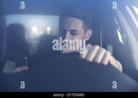 Businessman texting on his mobile phone while driving. Dangerous driver Stock Photo