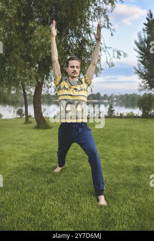 Man performing yoga young fitness man outdoor doing exercise. leg stretch Stock Photo