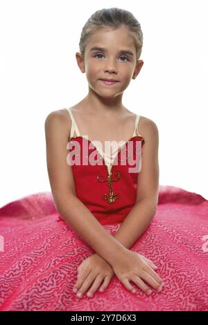 Portrait of a beautiful little ballerina in a performance red dress dreaming to become professional ballet dancer. isolated on the white background Stock Photo