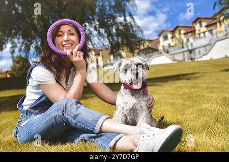 Caucasian joyful woman playing with her beloved dog in the park. The concept of love for animals. best friends. Dog breed Schnauzer Stock Photo