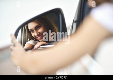 Portrait of cute smiling girl sit in the .car and look at the car mirror Stock Photo