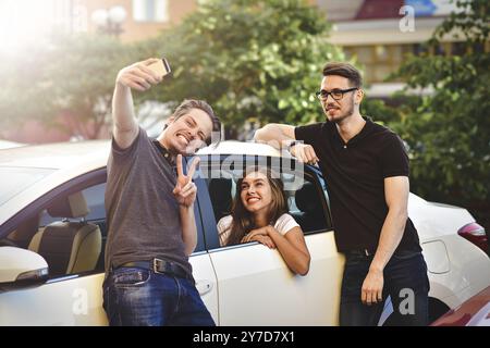 Three friends having fun taking a conversation near the car Stock Photo