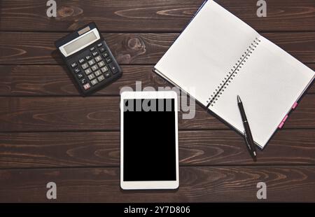 Top view of tablet, smartphone, calculator, notepad on wooden background, planning personal income, financial concept. typing on the calculator for mo Stock Photo