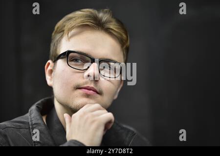 Serious young caucasian man wearing black glasses looking up and thinking Stock Photo