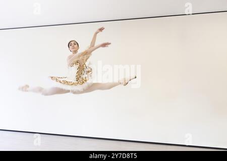 A young charming ballerina does ballet exercises in a jump in the ballet studio Stock Photo