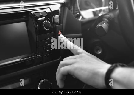 Man sits in car and push on red emergency button, black and white Stock Photo