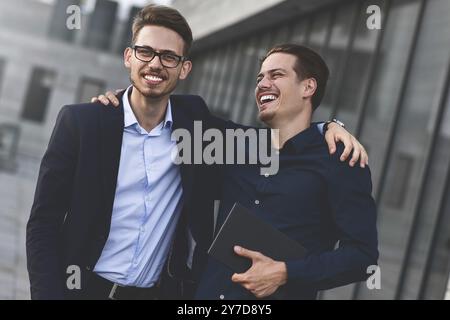 Two smiling colleagues speaking and having fun at street Stock Photo
