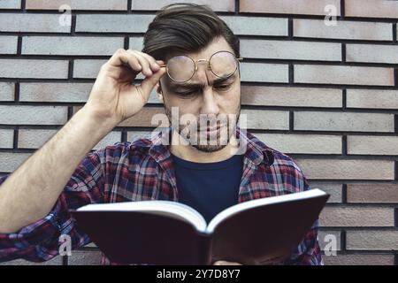 Portrait of smiling handsome man in round glasses and shirt isolated on brown brick wall Stock Photo