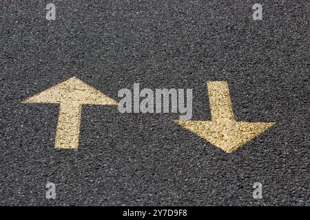 Yellow arrows on the asphalt road, back and forth Stock Photo