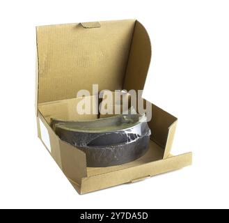 Brown cardboard box with car brake pads isolated on white background. Spare parts for transport Stock Photo