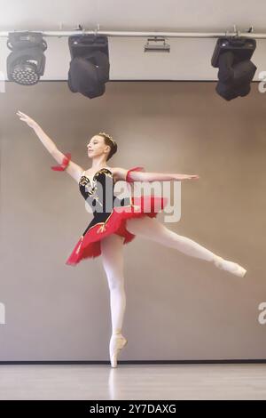 Teenager ballerina stands gracefully in pointe shoes on her toes in the studio.Ballet student practicing classical dance in studio before performance Stock Photo