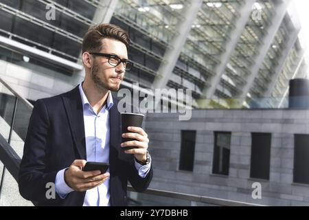 Handsome successful businessman in elegant suit outdoors stand at street in the city with coffee Stock Photo